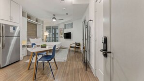 Et moderne køkken med indbygget køleskab, et spiseområde med bord og stole, samt en lille opholdsstue med en sofa.