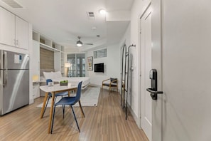 A modern kitchen with a built-in refrigerator, a dining area with a table and chairs, and a small seating area with a sofa. - Studio Balcony room in Downtown Austin | Pool & Parking | Near 3rd Street (Austin)