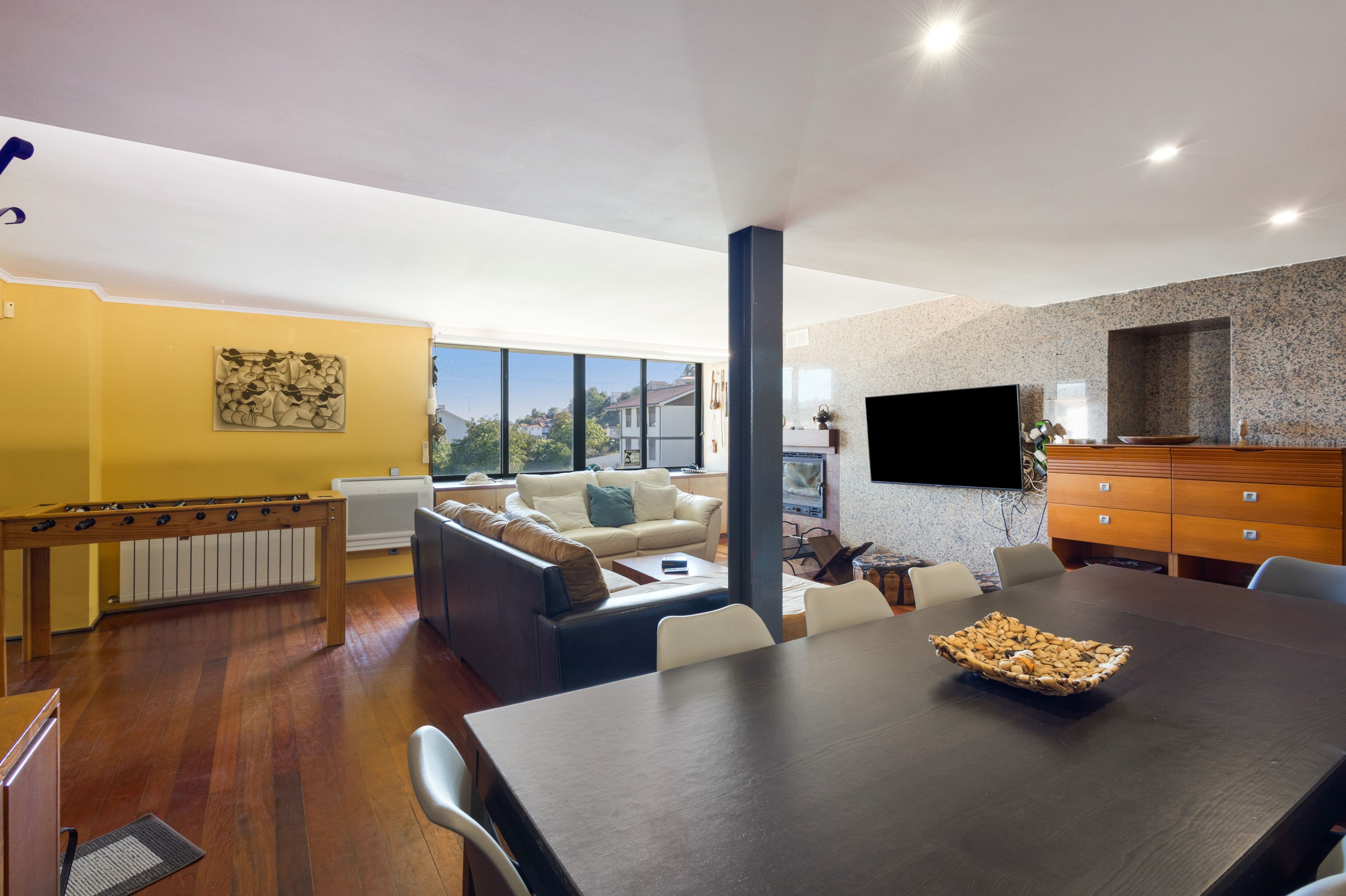 Een moderne woonkamer met een bank, een eettafel en een open haard.