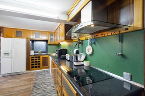 Une cuisine moderne avec des meubles en bois, un four encastré et un mur végétal.