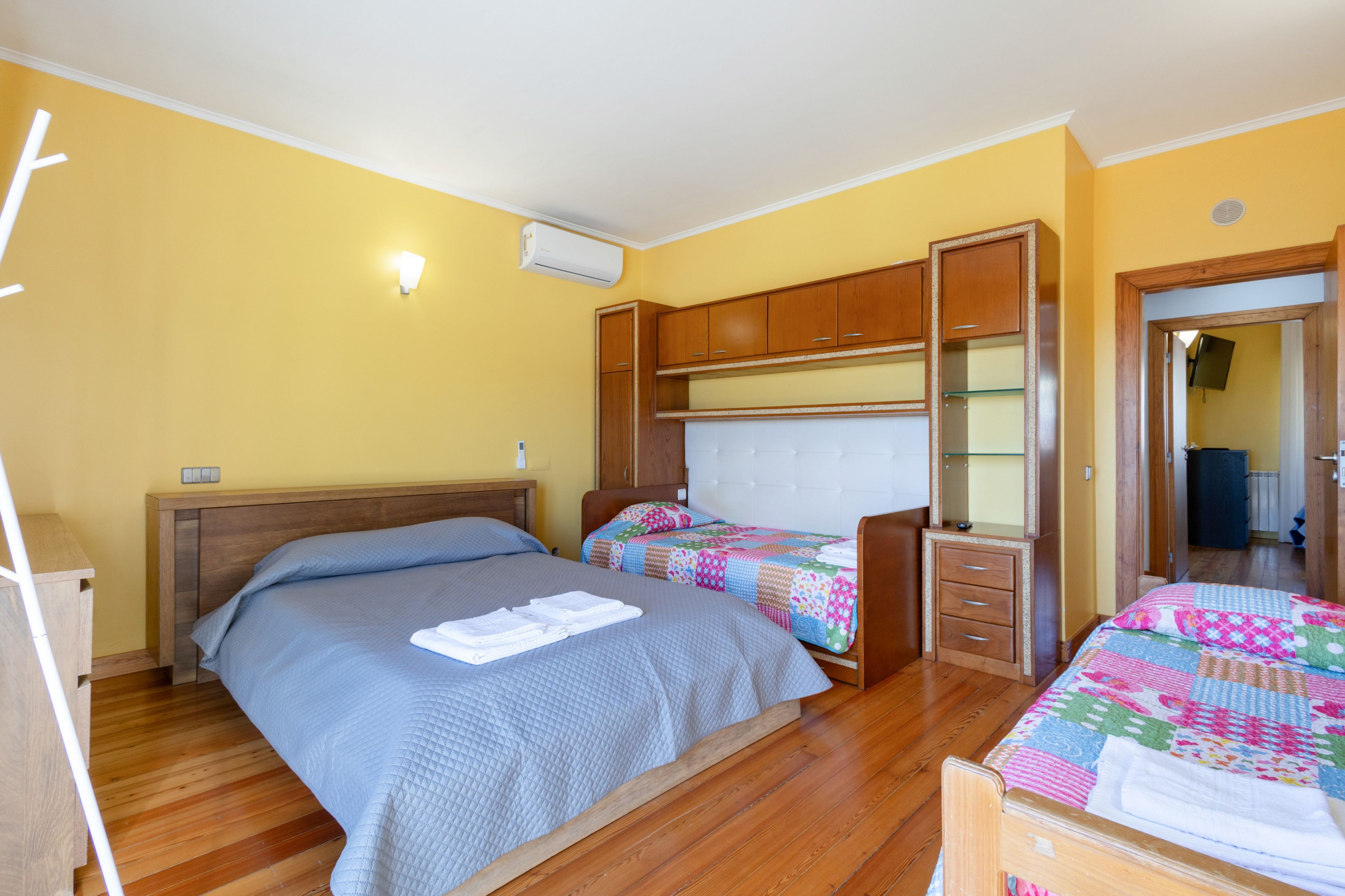 Een slaapkamer met twee bedden, houten meubels en een airconditioner.