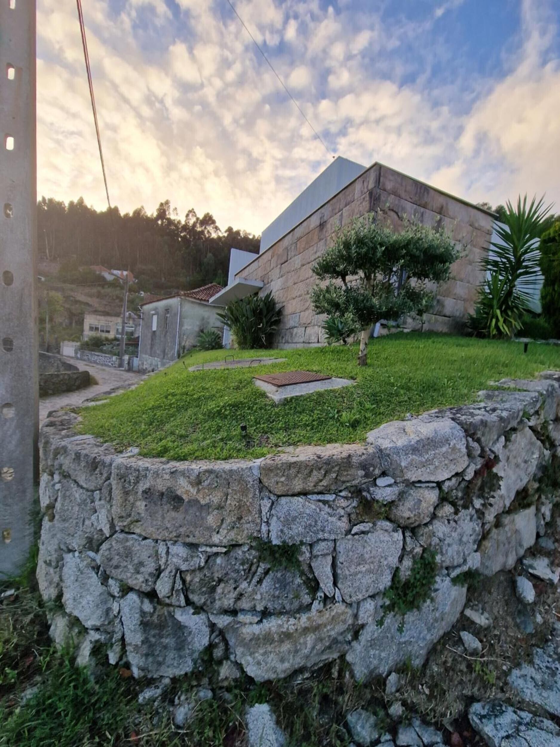 A stone wall with a grassy area and a building with a flat roof.