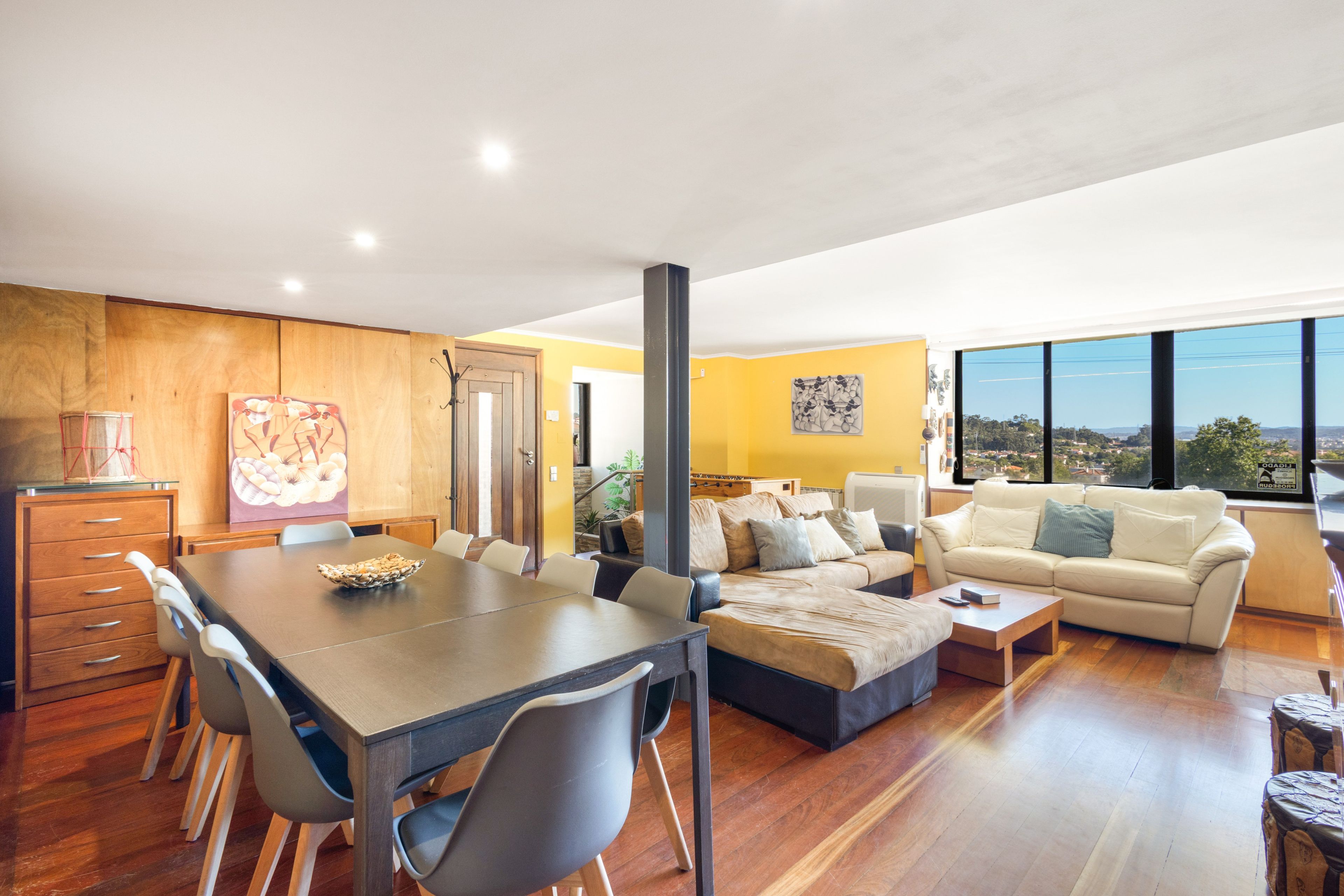 Un amplio espacio de sala con una mesa de comedor, sofás y vistas a través de grandes ventanales.