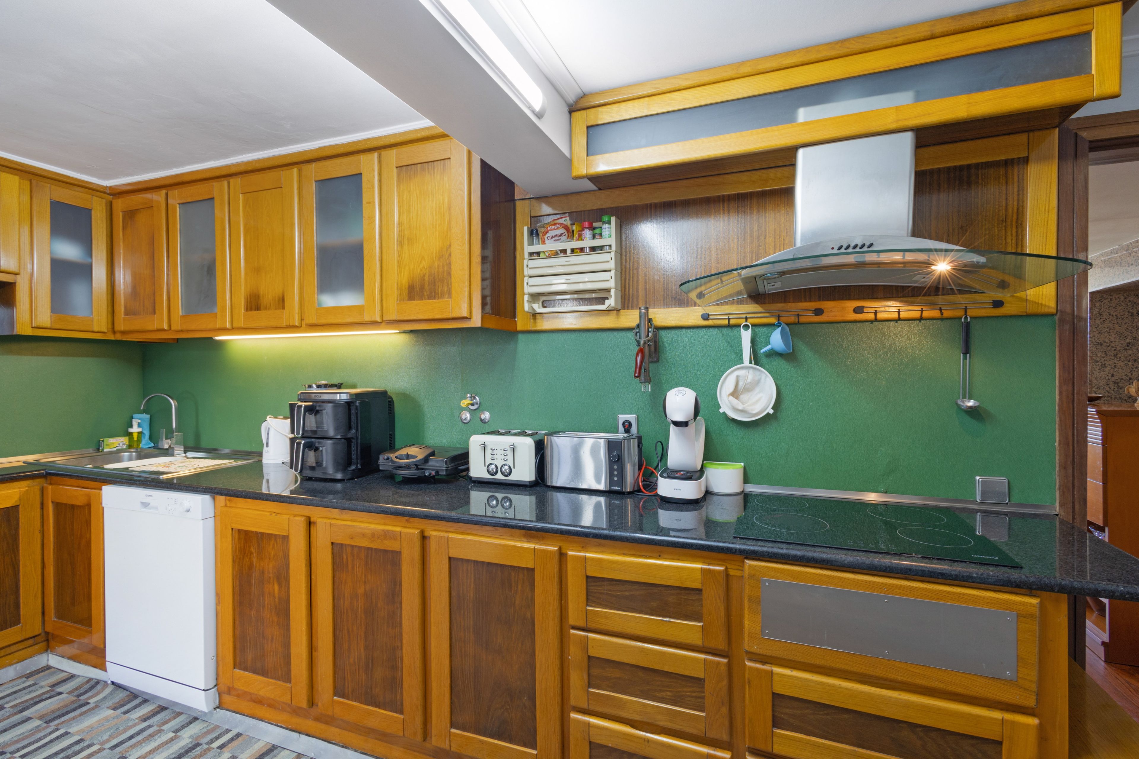 Una cocina con armarios de madera, cafetera, tostadora y microondas.