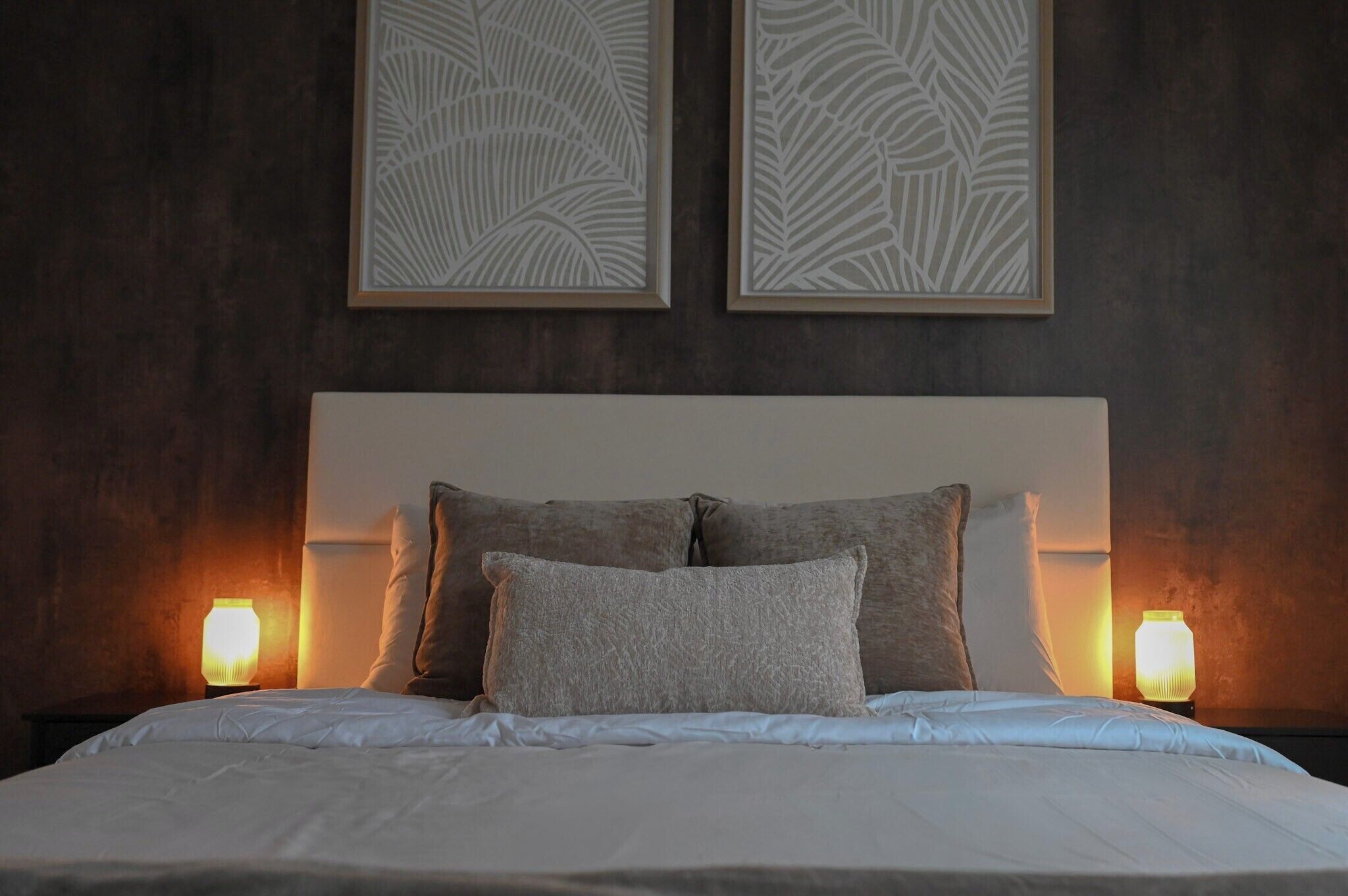 A bed with white linens, two pillows, and two bedside lamps.