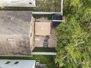 Eine Vogelperspektive auf ein Dach mit einer Terrassenfläche, inklusive Tisch und Stühlen, umgeben von Grünpflanzen und einem Gebäude.