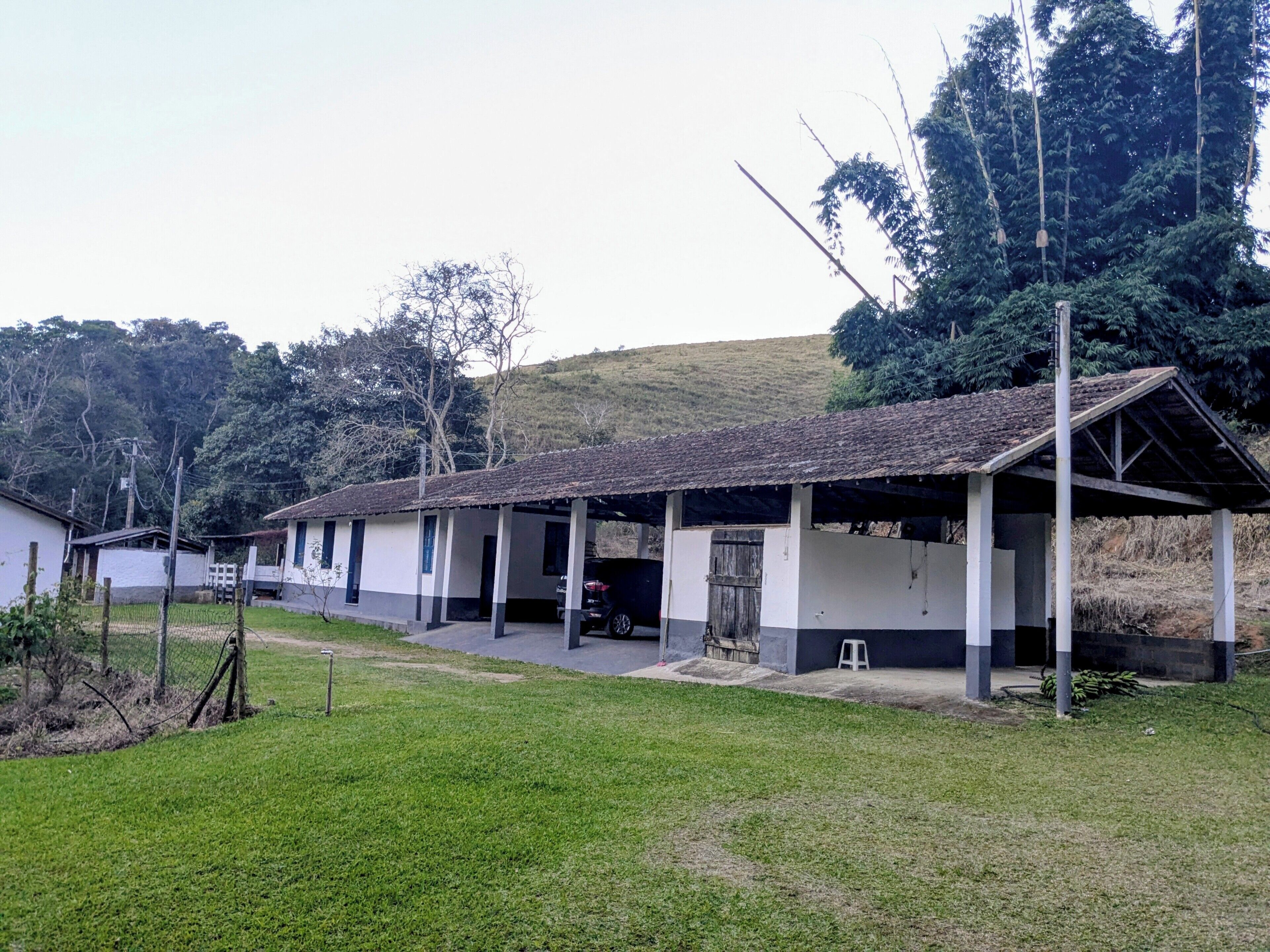 A single-story building with a covered porch, a small front yard, and a hill in the background.