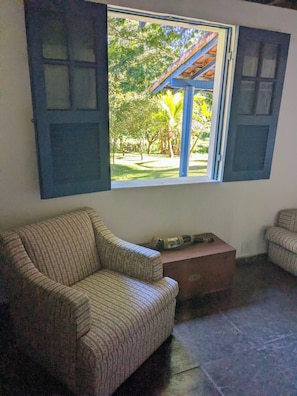 A room with a sofa, a small table, and a window with open shutters.