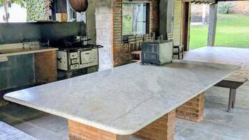 An outdoor kitchen area with a large marble countertop, a brick oven, and a grill.