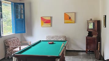 Quarto com mesa de bilhar, teto de madeira e obras de arte nas paredes.