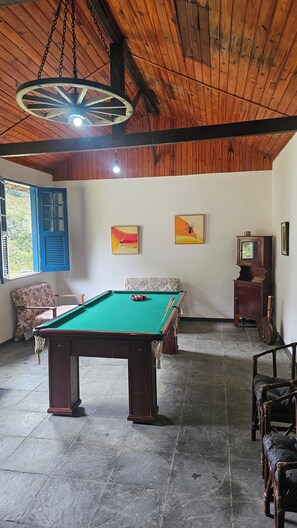 A room with a pool table, wooden ceiling, and artwork on the walls.