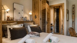 Ein Hotelzimmer mit einem Bett, Kissen, einem Nachttisch mit Lampe, einem Wandbild und einer Holztür.