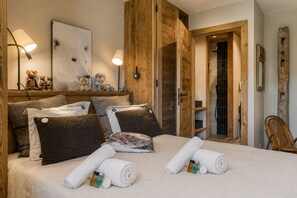 Ein Hotelzimmer mit einem Bett, Kissen, einem Nachttisch mit Lampe, einem Wandbild und einer Holztür.