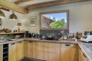 Eine Küche mit Holzausstattung, einem großen Fenster und diversen Küchengeräten.