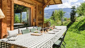 Eine Holzhütte mit Esstisch, gedeckt für vier Personen, mit Blick auf eine Berglandschaft.