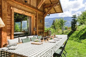 Eine Holzhütte mit Esstisch, gedeckt für vier Personen, mit Blick auf eine Berglandschaft.
