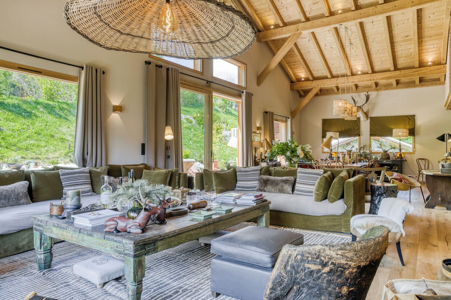 A spacious living area with a large window, a rustic wooden ceiling, and a variety of seating arrangements.