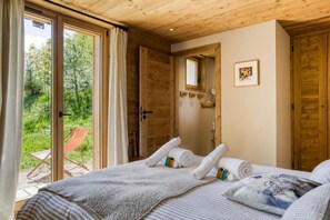 Ein Schlafzimmer mit einem Bett, Handtüchern und einem Fenster mit Blick auf Grünflächen.