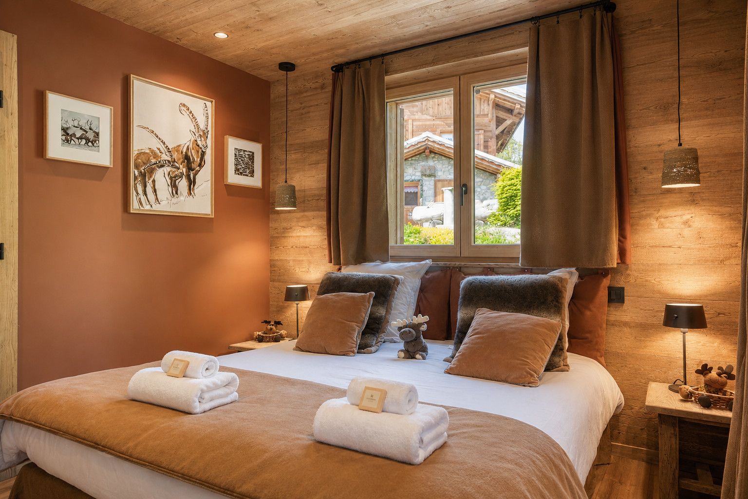 A cozy bedroom with a large bed, wooden walls, and artwork.