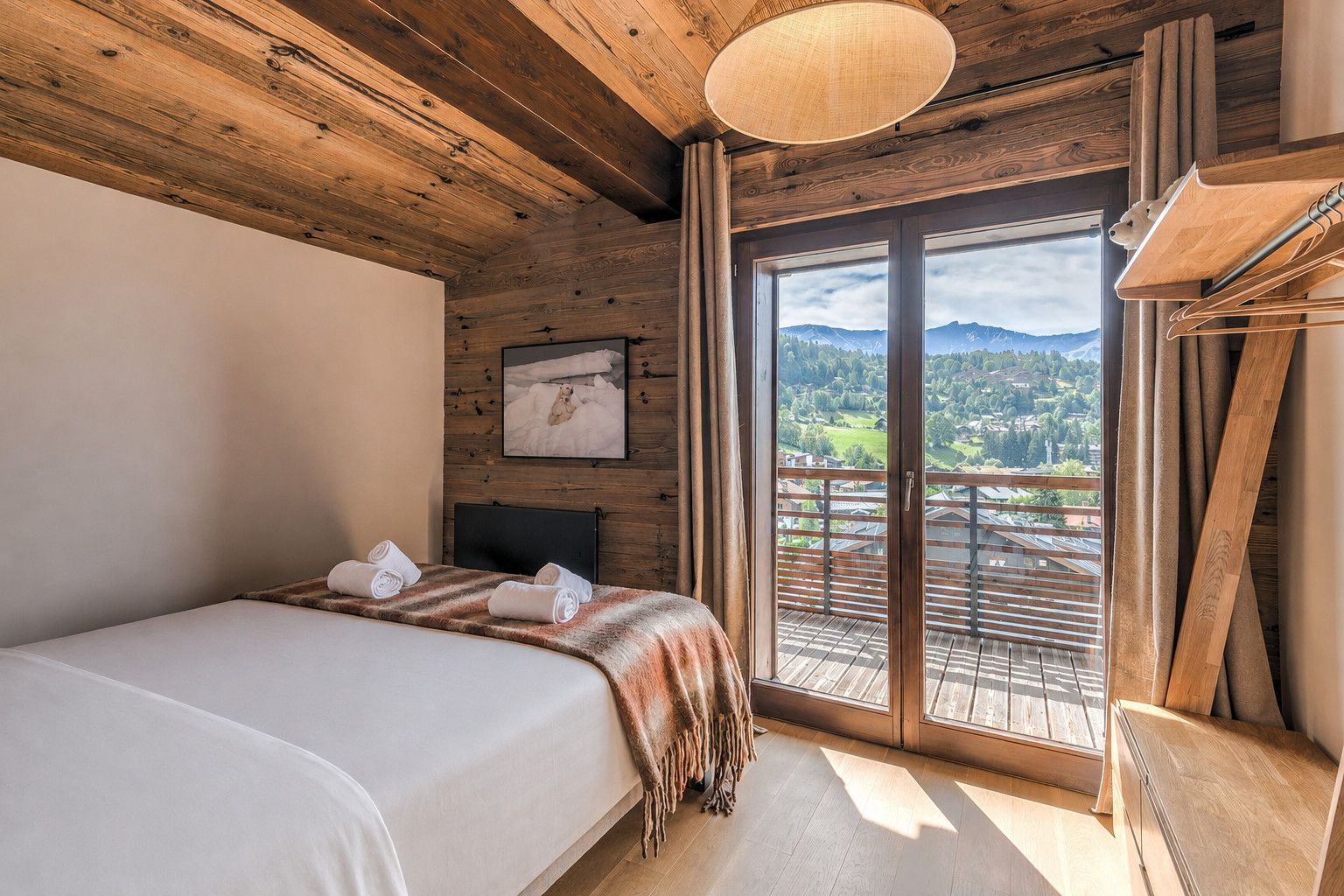 Une chambre d’hôtel avec un lit, une fenêtre donnant sur les montagnes et un plafond en bois.