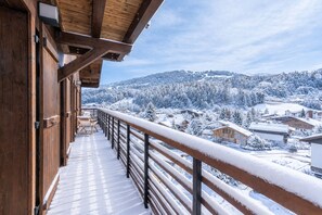 A wooden balcony with a metal railing overlooking a snow-covered village and mountains. - Le Duplex des Sommets - Welkeys (Demi-Quartier)