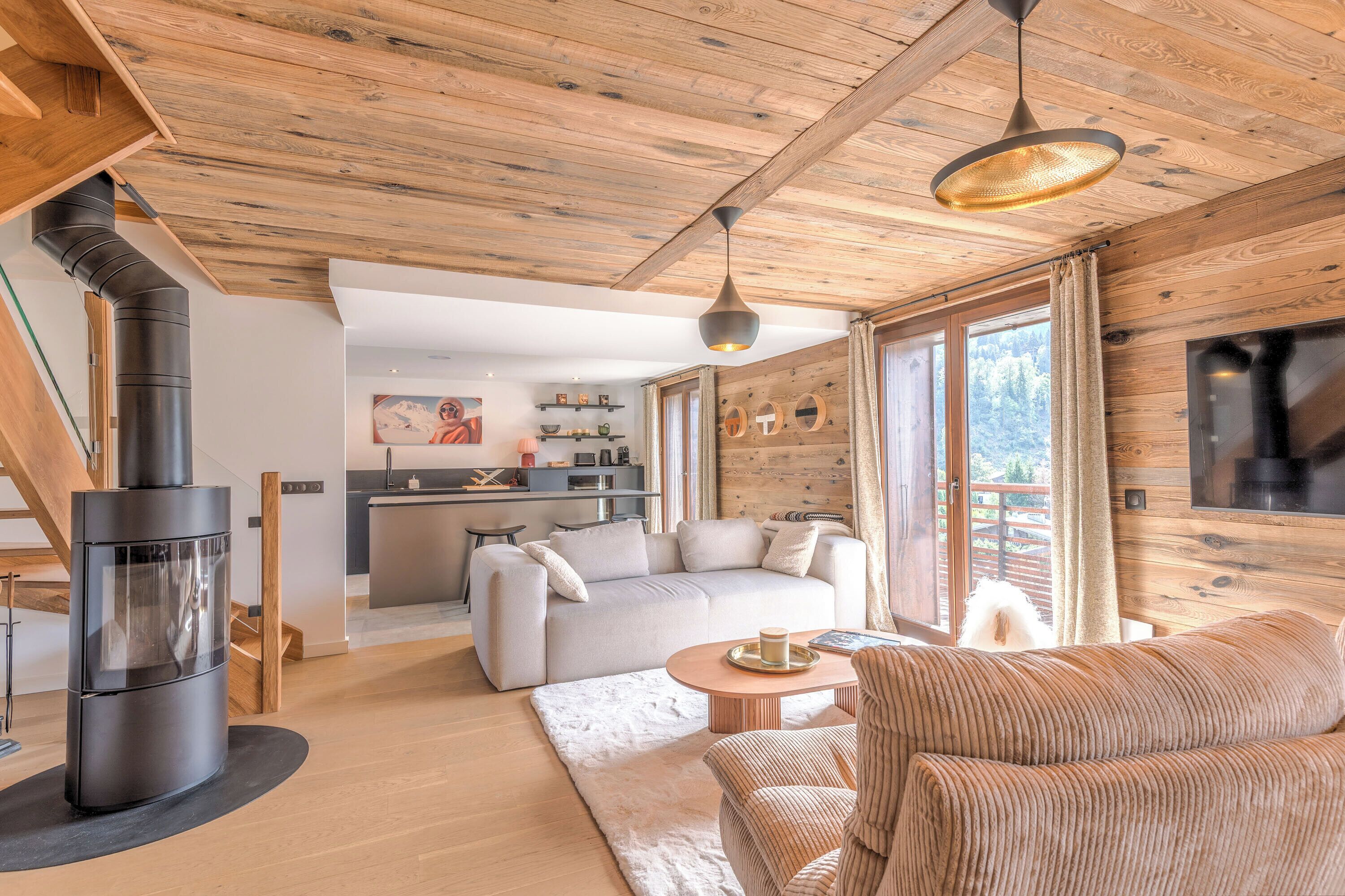 A modern living room with a fireplace, sofa, and a view of the kitchen and outdoors.