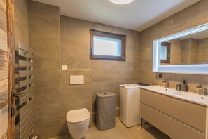 A modern bathroom with a toilet, a washing machine, and a large mirror. - Le Duplex des Sommets - Welkeys (Demi-Quartier)