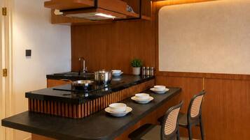 A modern kitchen with a central island, black countertops, wooden paneling, and a built-in stove.