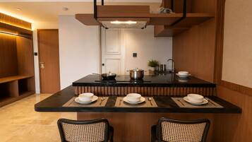Uma cozinha moderna com uma ilha central, duas cadeiras e uma mesa de jantar posta para quatro pessoas.