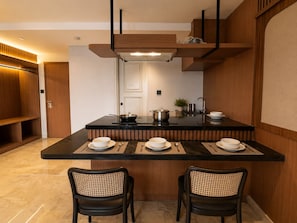 Uma cozinha moderna com uma ilha central, duas cadeiras e uma mesa de jantar posta para quatro pessoas.