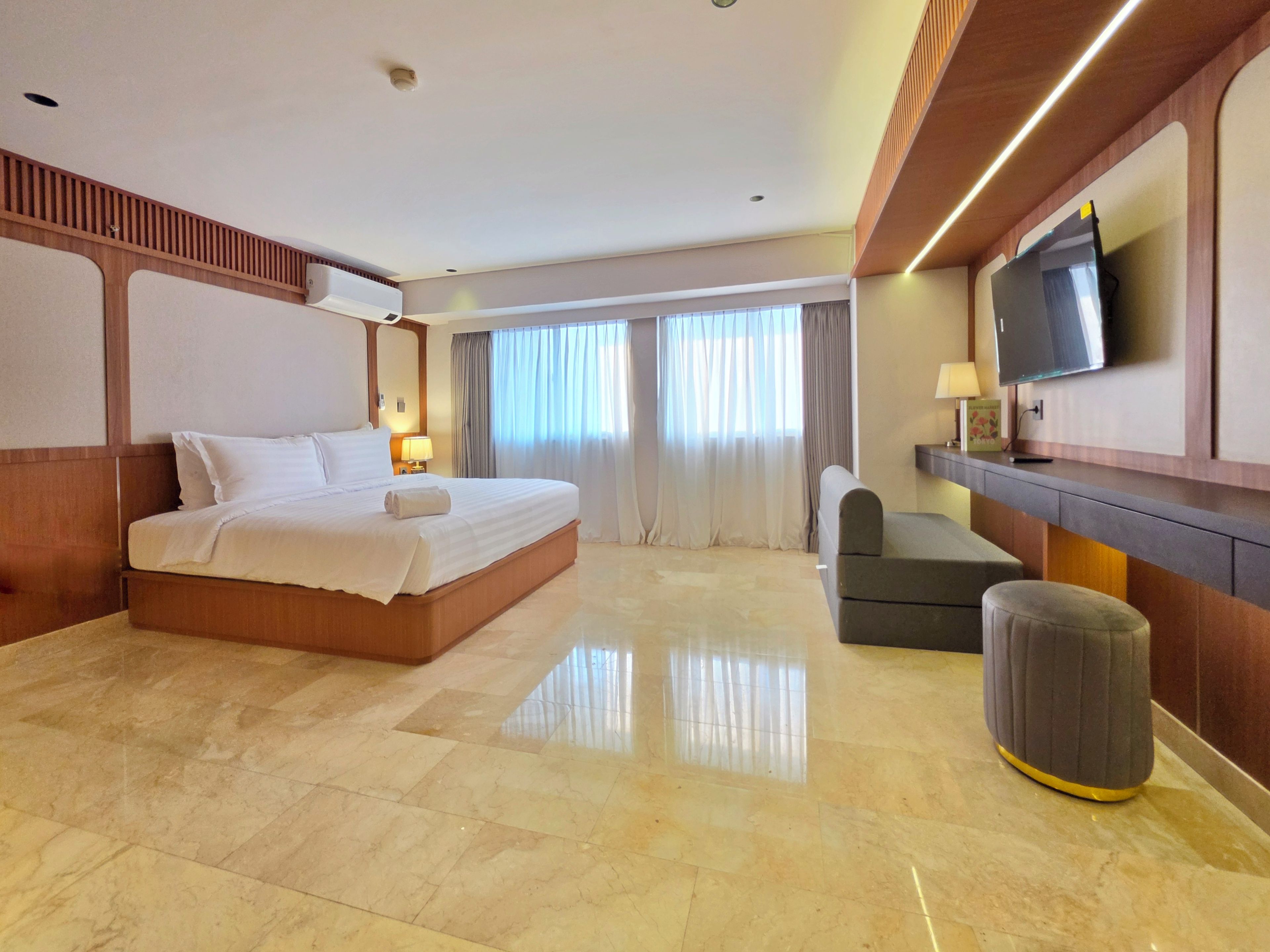 Ein Hotelzimmer mit einem großen Bett, einem Fernseher, einem Schreibtisch und einem Sessel.