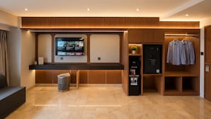 Un moderno vestíbulo de hotel con una recepción, una pantalla digital mostrando contenido, un perchero y una máquina expendedora.