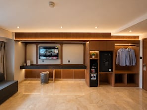 Um saguão de hotel moderno com balcão de recepção, uma tela digital exibindo conteúdo, um porta-casacos e uma máquina de venda automática.