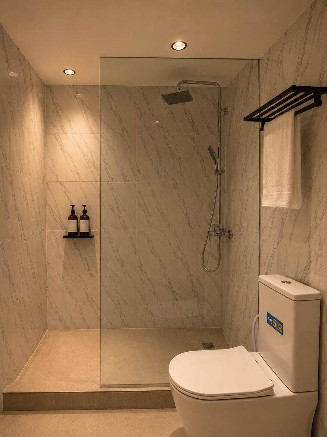 A modern bathroom with a glass-enclosed shower, a toilet, and a shelf with toiletries.