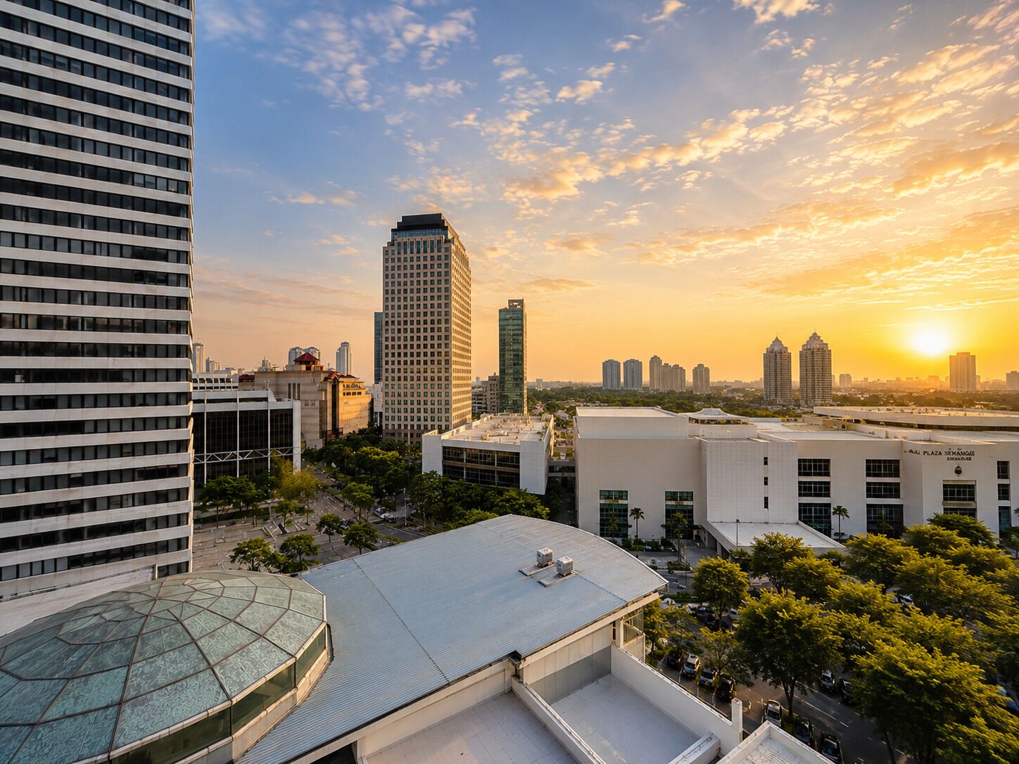 A cityscape with modern buildings, a clear sky, and a sunset.