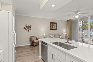 A modern kitchen with a built-in sink, a ceiling fan, and a view of the outside. - Destin West ~ Sandpiper L07 ~ Walk Out Lanai with Private Grill ~ Lazy River (Fort Walton Beach)