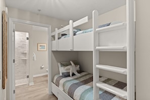 A bunk bed with a lower bunk, a door leading to a bathroom, and a framed picture on the wall. - Destin West ~ Sandpiper L07 ~ Walk Out Lanai with Private Grill ~ Lazy River (Fort Walton Beach)