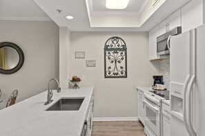 Una cocina moderna con encimera de mármol, electrodomésticos de acero inoxidable y un elemento decorativo en la pared.