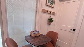 Una habitación con una mesa redonda de madera, dos sillas de cuero marrón, una planta pequeña y un cuadro en la pared.