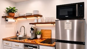 Una cocina moderna con microondas integrado, refrigerador de acero inoxidable y encimera de madera.