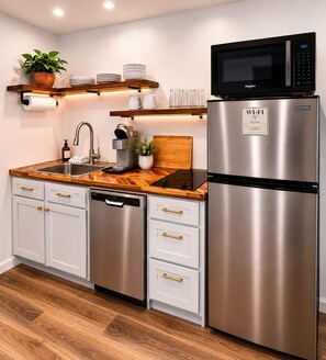 Een moderne keuken met een ingebouwde magnetron, een koelkast van roestvrij staal en een houten aanrecht.