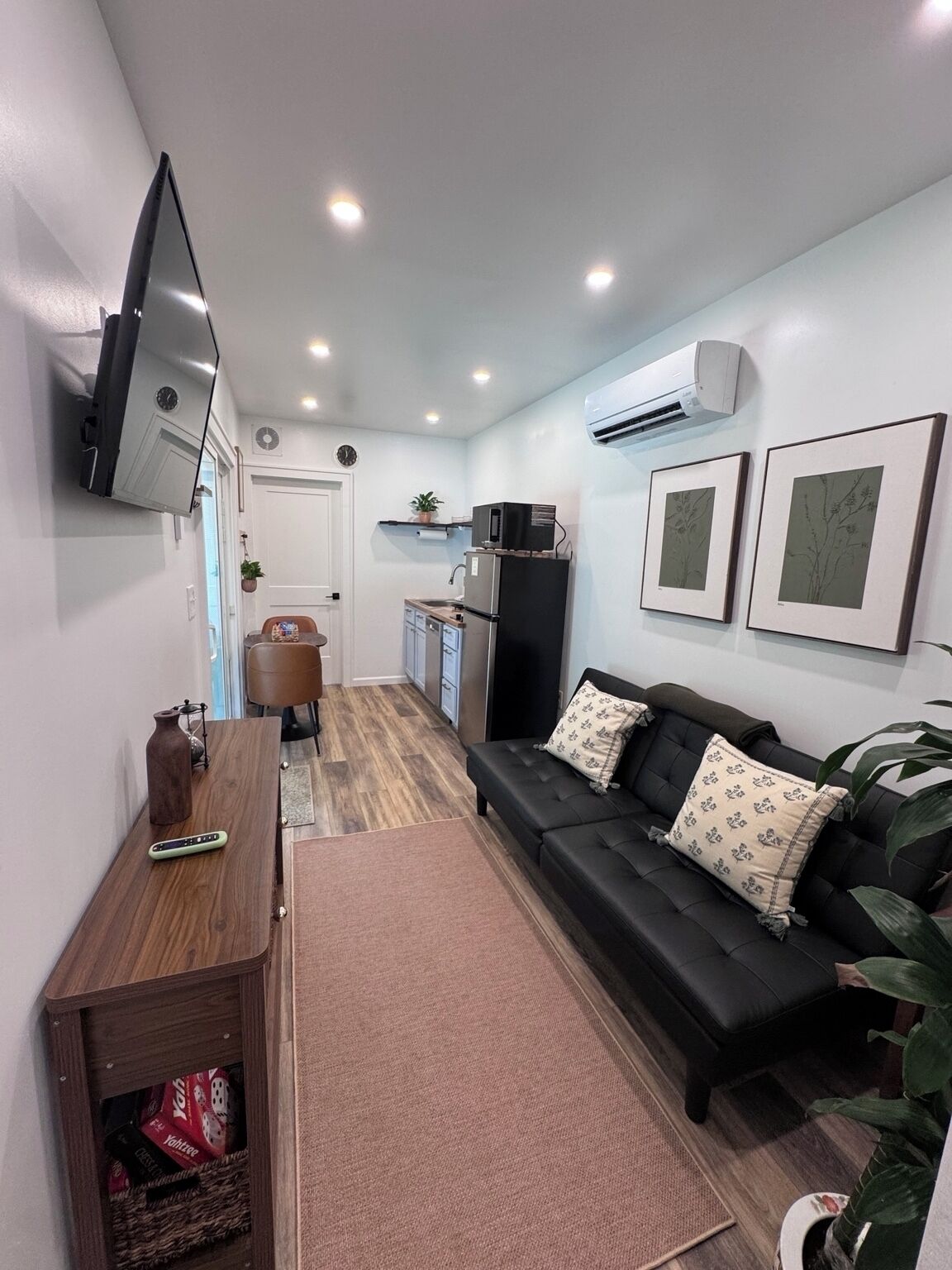 A compact living space with a sofa, a television, a kitchen area, and a dining table.