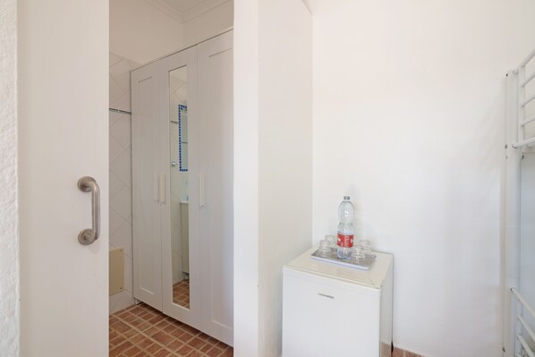 A bathroom with a white door, a small white cabinet, and a water dispenser.