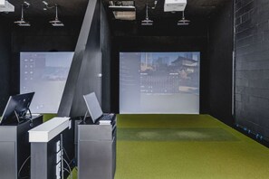 Een moderne kantoorruimte met een groen tapijt, meerdere werkplekken en grote ramen met uitzicht op de stad.