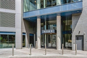 A modern building entrance with a sign reading 'AQUA II' and a glass facade. - The Aqua Vista | 2 Bed, Lake Views w Pool, Hot tub (Kelowna)