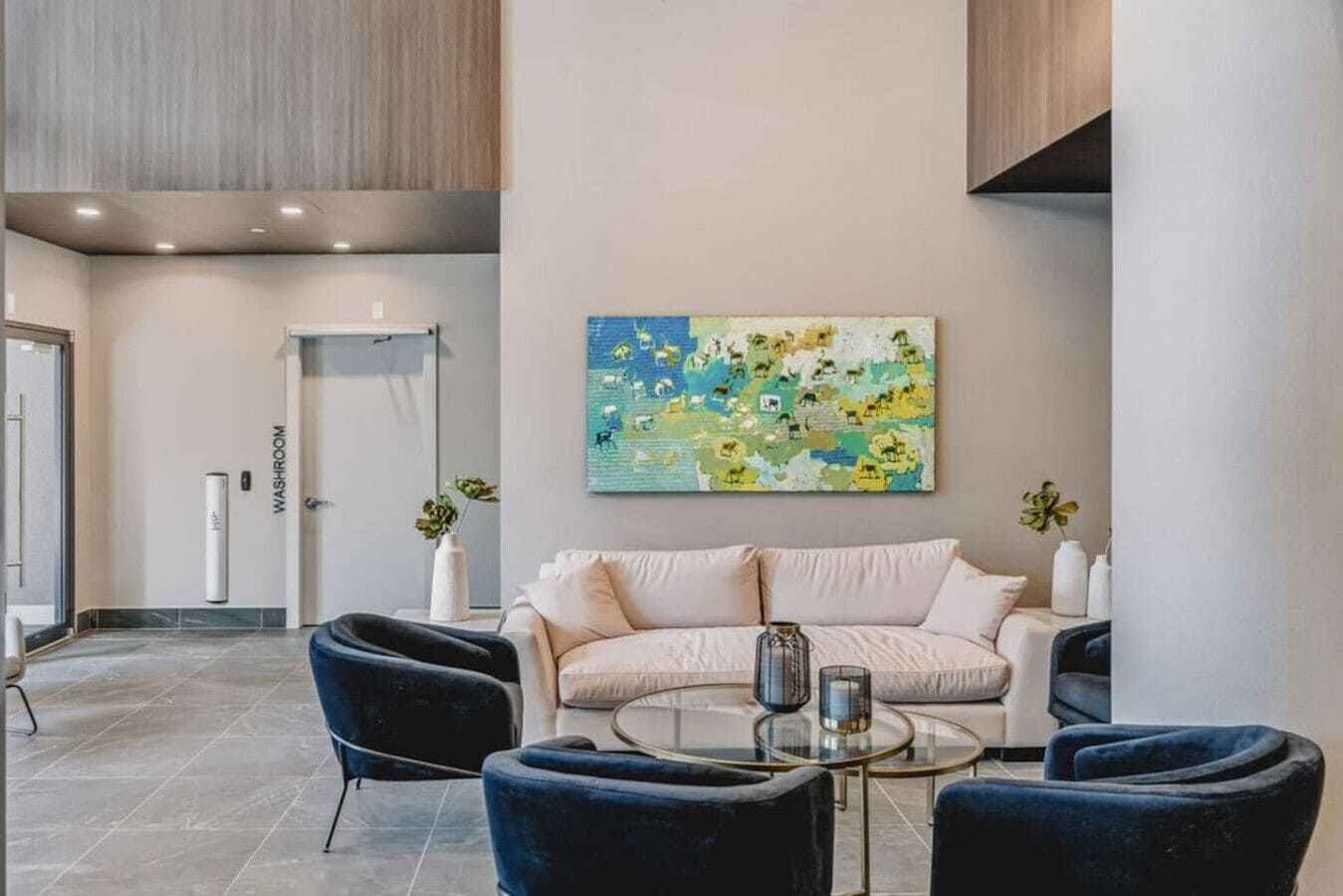 Ein modernes Interieur mit einem Sofa, zwei Sesseln, einem Couchtisch und einem Wandbild.