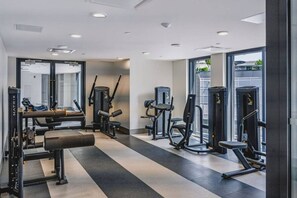 Ein modernes Fitnessstudio mit unterschiedlichen Trainingsgeräten, großen Fenstern und einem sauberen, gut beleuchteten Innenraum.