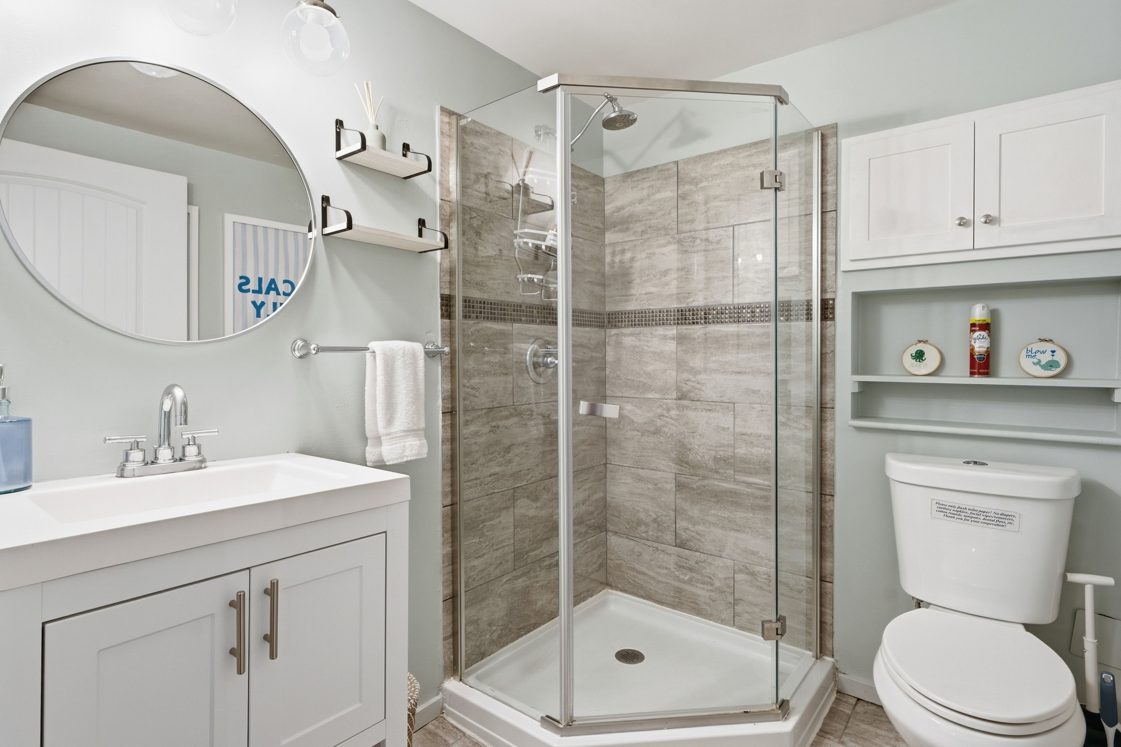 Une salle de bain avec une douche à parois de verre, un lavabo blanc et des toilettes.