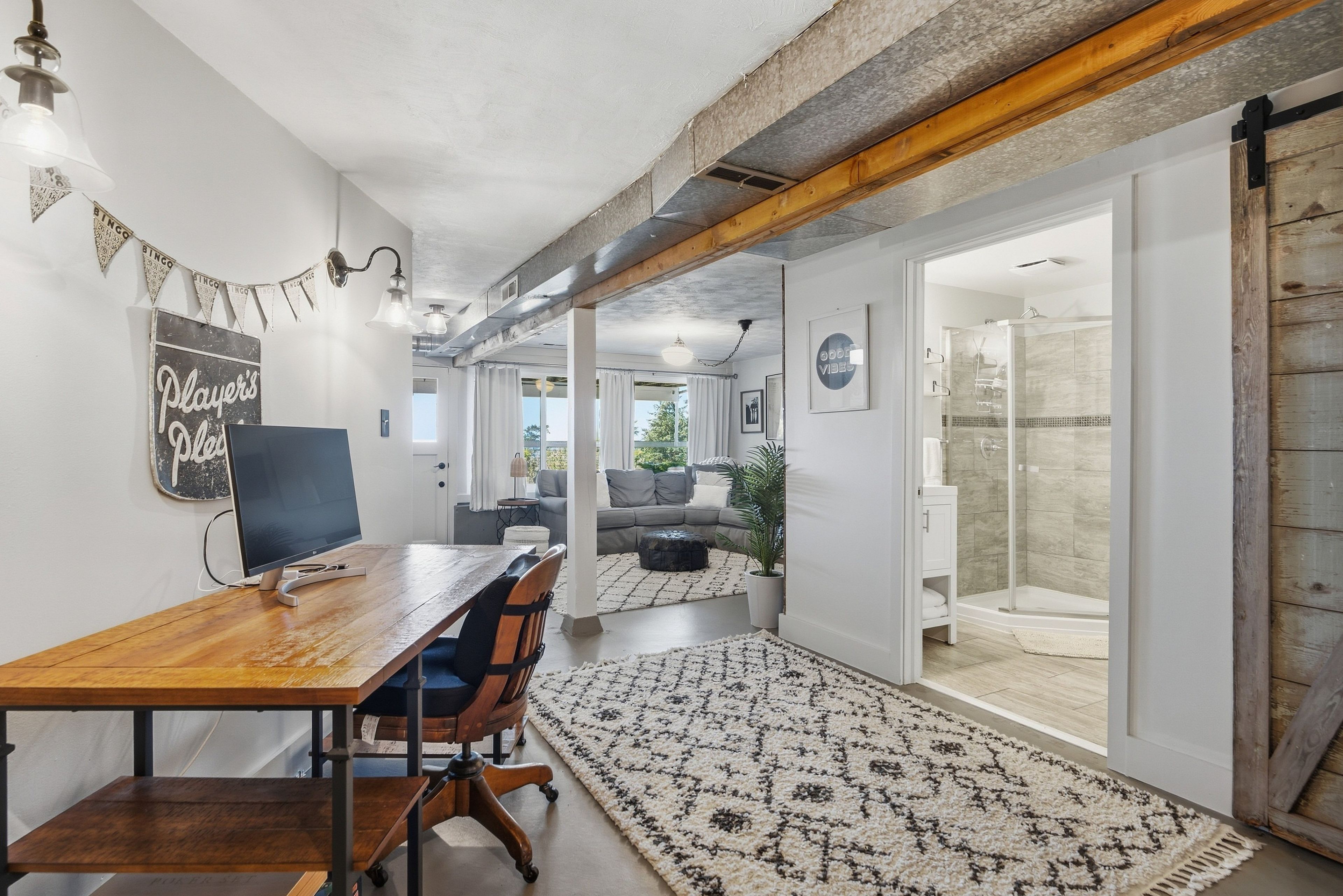 A modern interior with a wooden dining table, a television, and a patterned rug.
