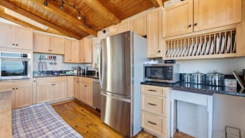 Una cocina moderna con armarios de madera, electrodomésticos de acero inoxidable y una zona de comedor con mantel escocés.